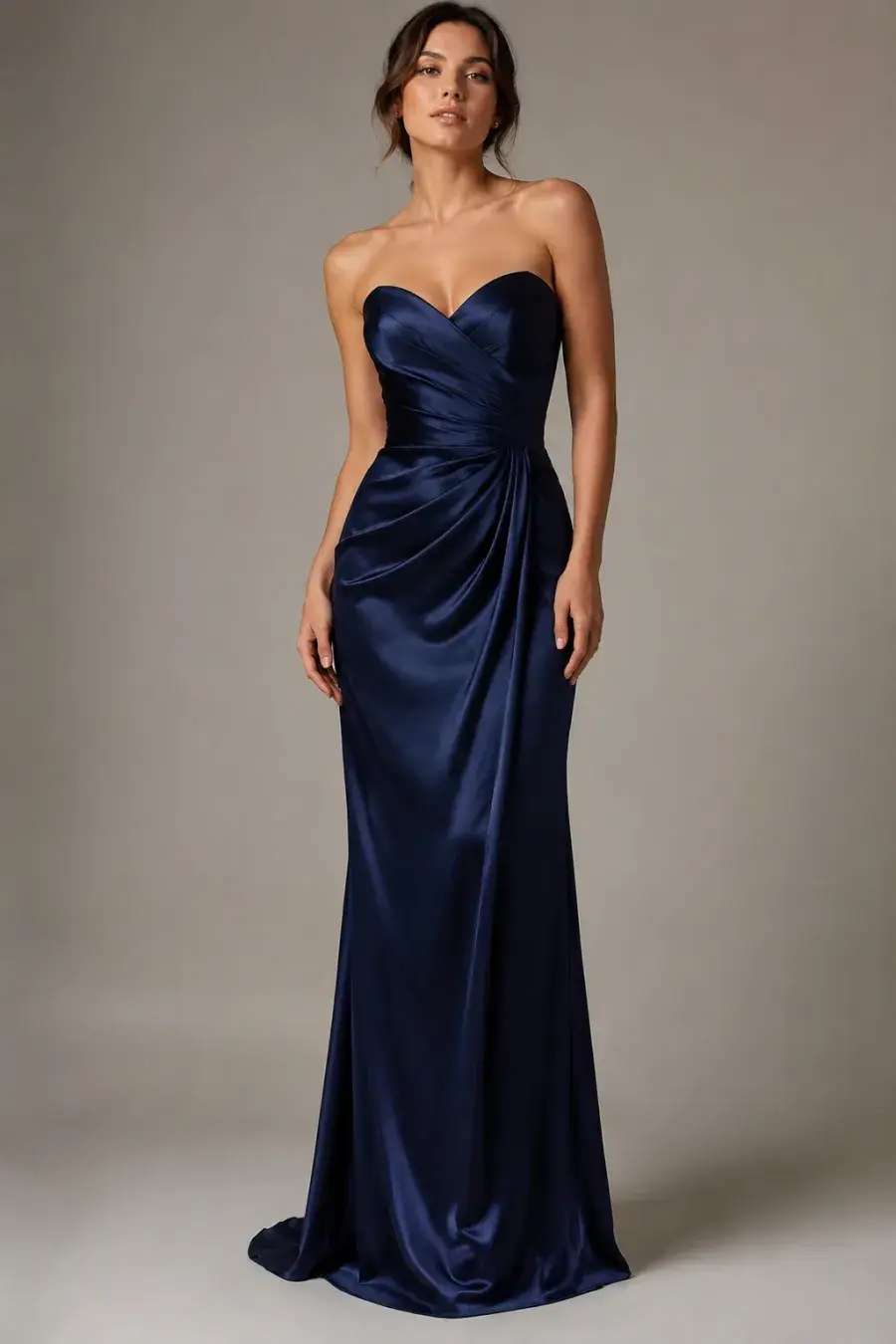 Full-length shot of a floor-length midnight-blue satin evening gown with a sweetheart neckline on a woman, shown on a plain studio background with soft lighting