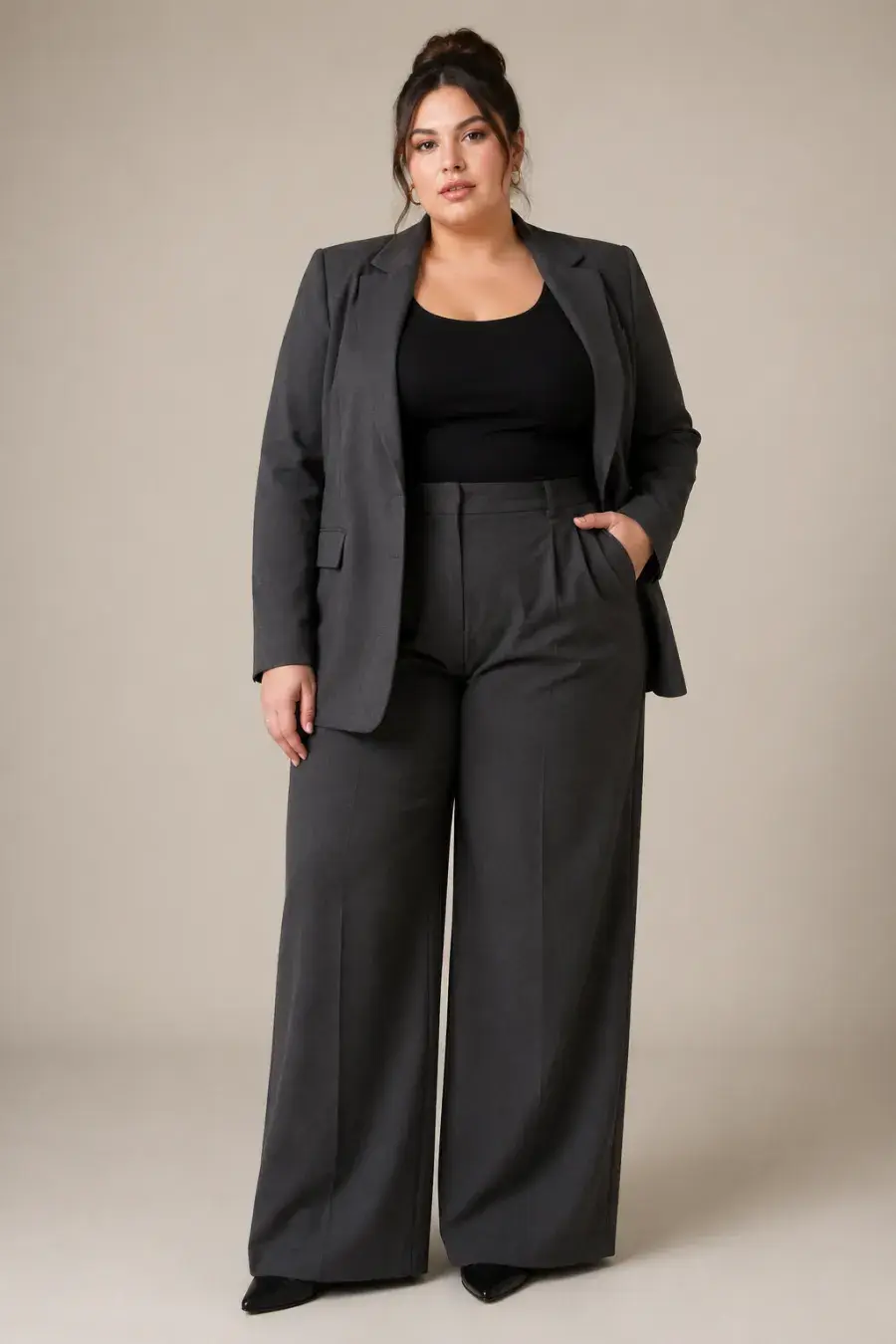 Full-body shot of a plus size business-casual look — a charcoal blazer over a fitted top with wide-leg trousers, on a plain studio background