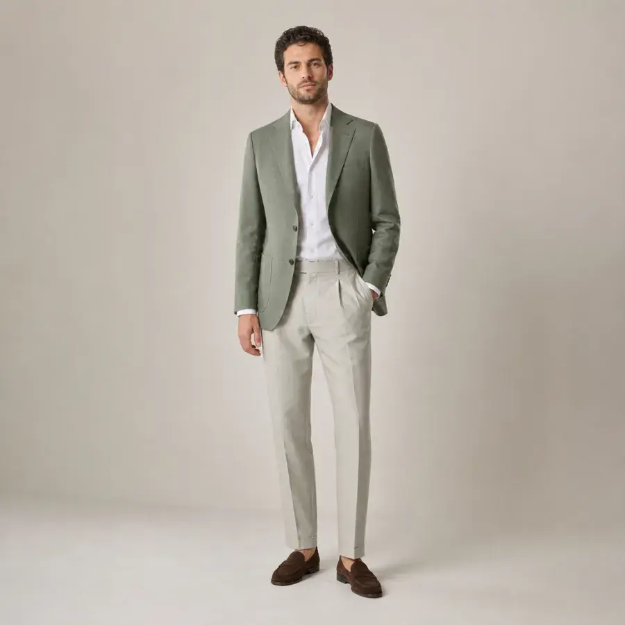 A man in his early thirties wearing a sage-green sport coat over a white open-collar shirt with stone-colored trousers and brown suede loafers, full body, entire figure from head to feet in frame, centered with headroom